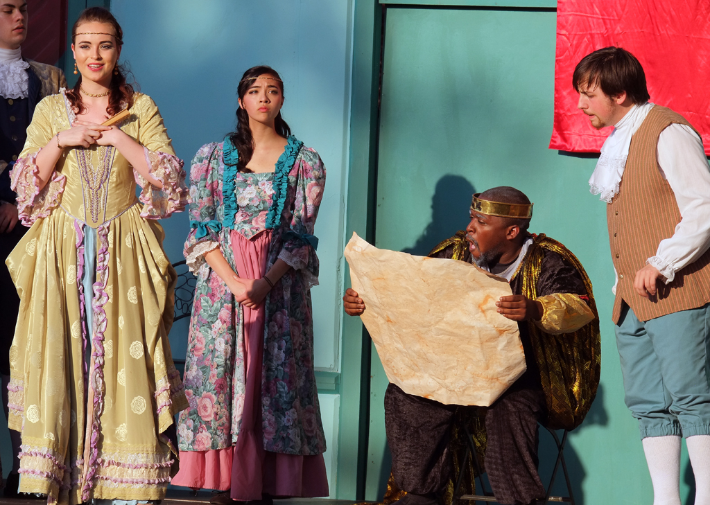 King Lear (Marcus Salley - center) decides to divide his kingdom among his three daughters but demands they declare how much they love him first. Goneril (Corinn Keene - far left) makes her disingenuous declaration.